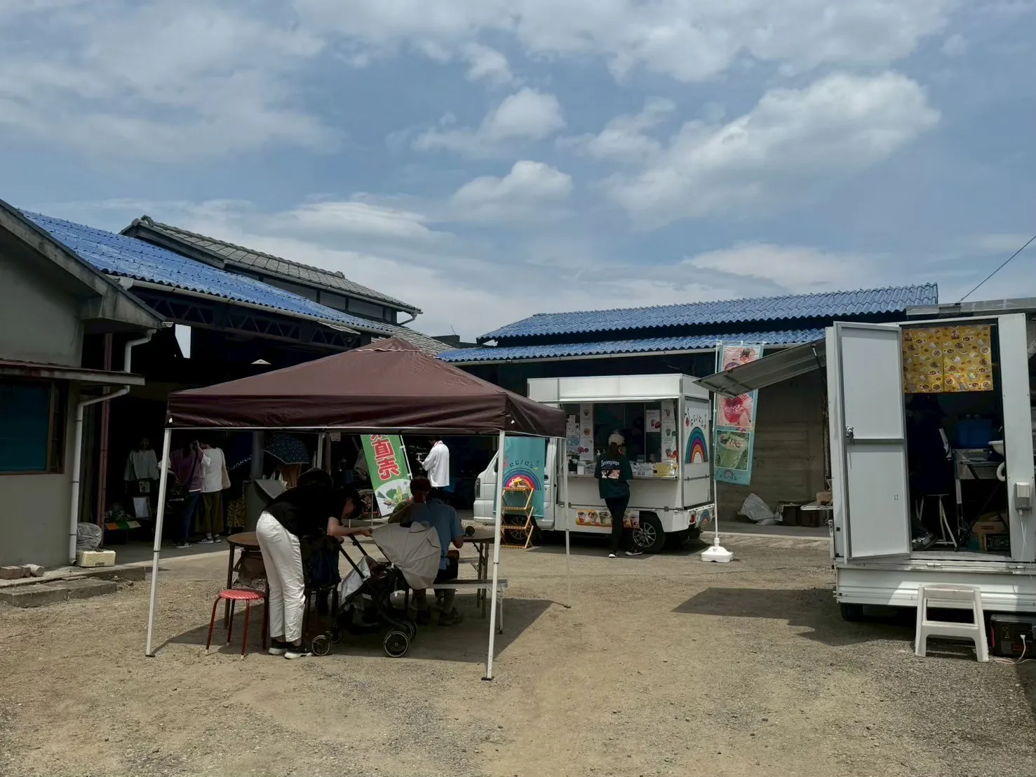 庭に張られた茶色いテントとキッチンカー。テントの下で誰かが楽器を弾いている