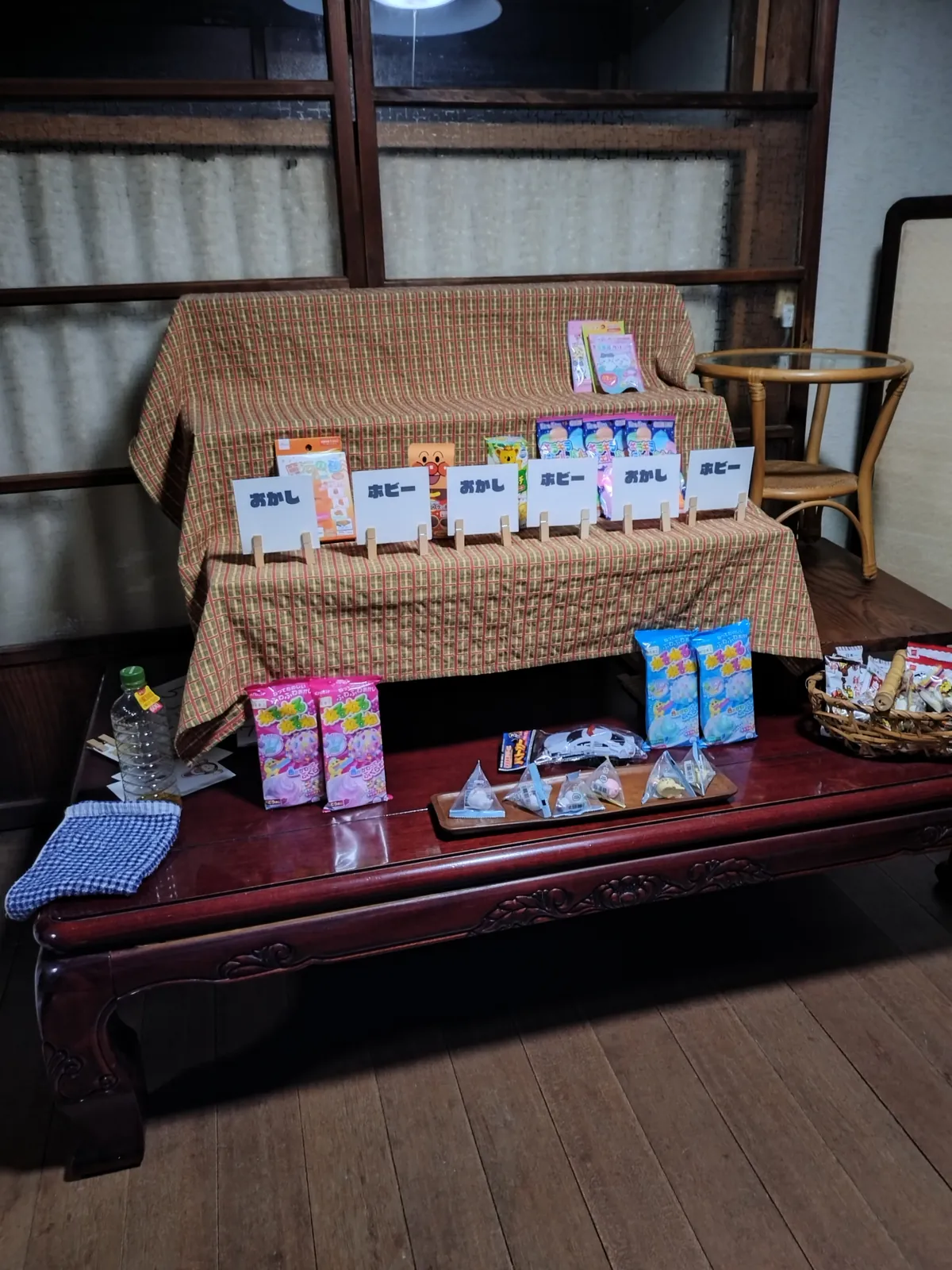 縁側の座卓に布をかけ、菓子や小物を並べた物販の台。人物なし