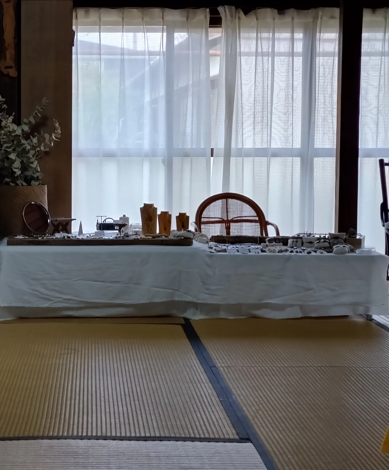 白い布をかけた台に小さな手仕事の品が並ぶ、和室の展示